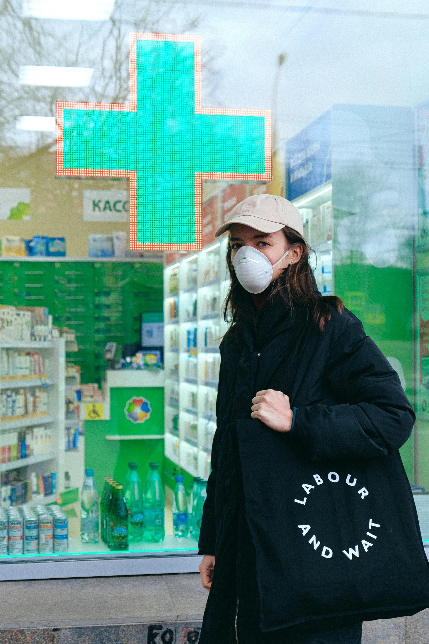 Masked customer standing outside a pharmacy storefront