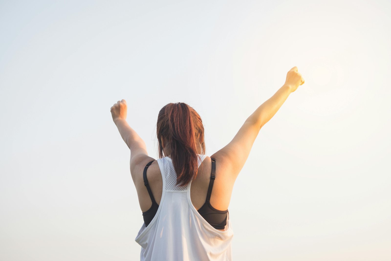Person raising both arms in an outdoor wellness moment